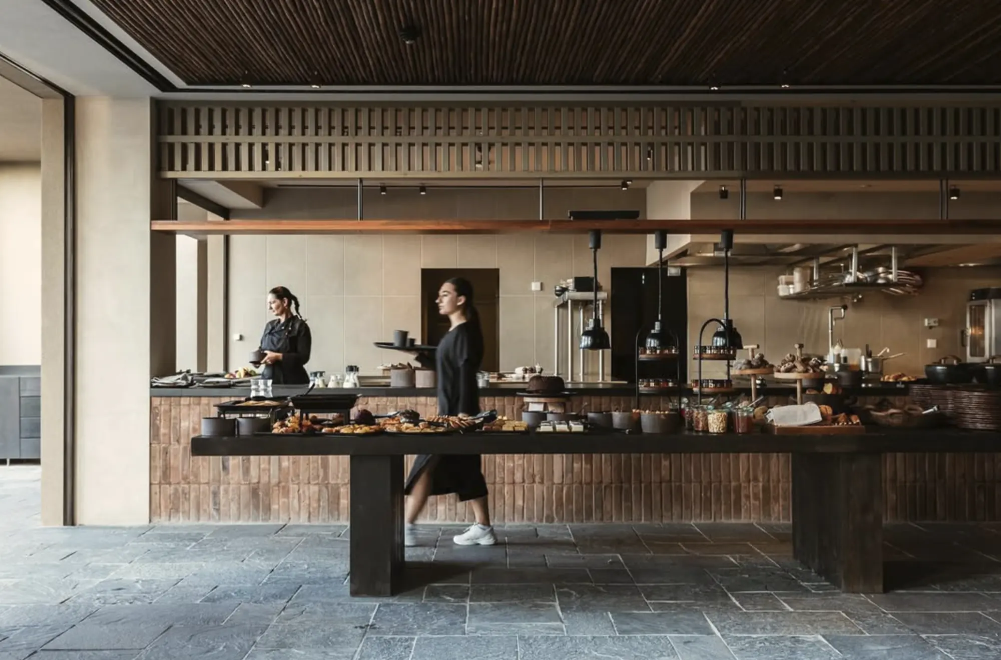 Long dark wood buffet with staff in front of a brick kitchen